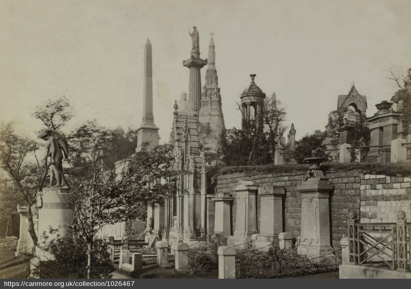 A sepia toned photo of monumental gravestones including angel sculptures, tall needle monuments and large columns 